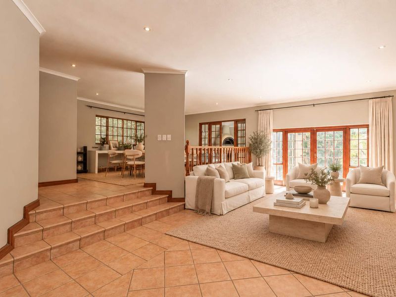 Spacious open-plan living area featuring tiled floors, a wooden balustrade, and large french doors that provide ample natural light and access to the outdoors.
