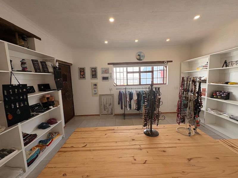 A versatile interior space featuring tiled flooring, recessed downlighting, and built-in shelving units, currently utilized as a retail or display area.