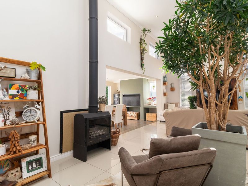 Spacious open-plan living area featuring high ceilings, large format tiled flooring, and a modern freestanding fireplace, creating a bright and airy atmosphere.