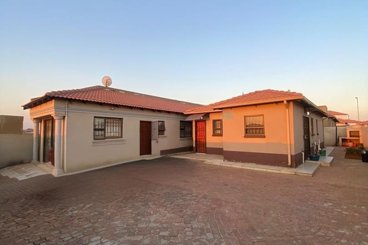 Rear view of the property featuring a paved courtyard, terracotta tiled roof, and an outdoor braai area.