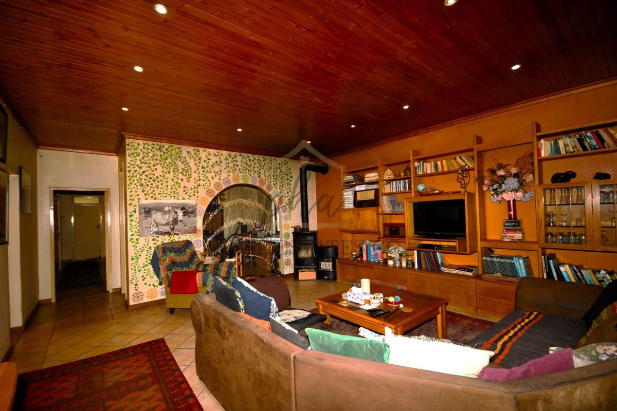 A cozy living room featuring a wood-burning fireplace, built-in wooden shelving, and a distinctive timber-paneled ceiling with recessed lighting.