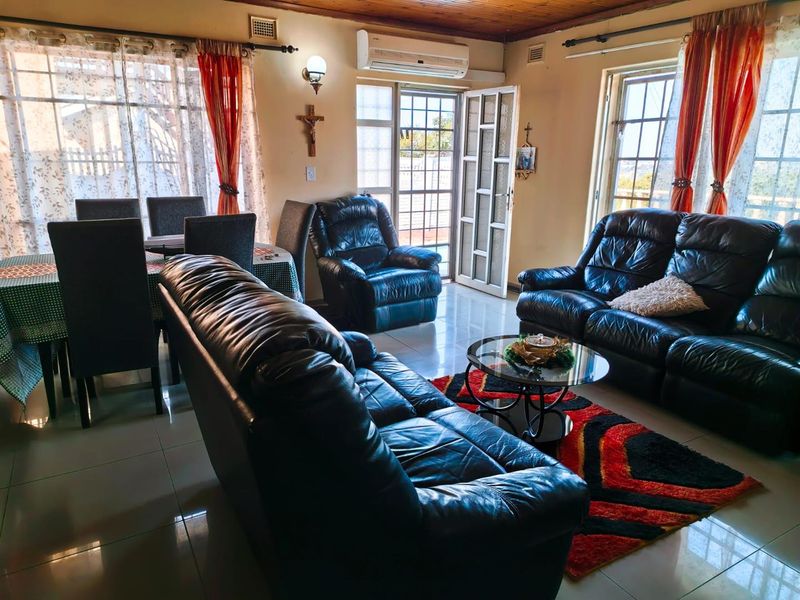 Open-plan living and dining area featuring tiled flooring, timber ceiling accents, and an integrated air conditioning unit with access to the exterior.