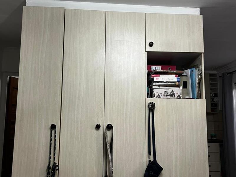 A bedroom featuring a light wood-grain built-in wardrobe with integrated shelving and overhead storage.