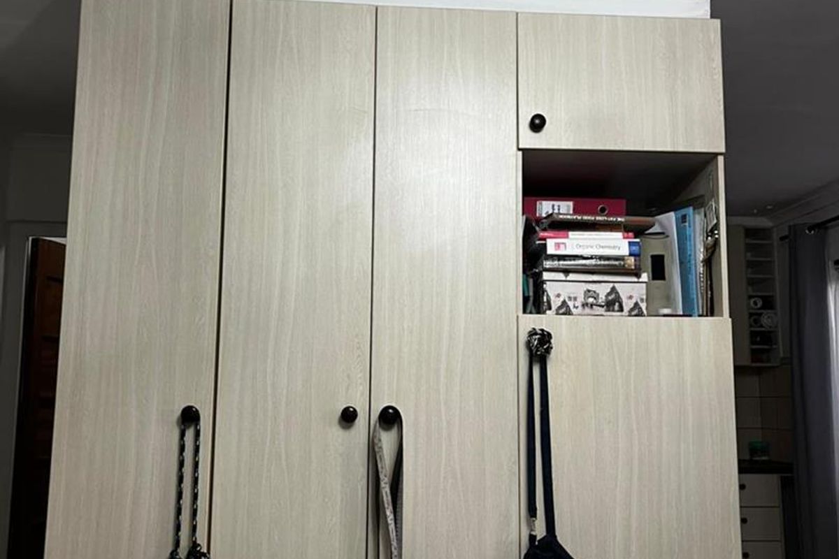 A bedroom featuring a light wood-grain built-in wardrobe with integrated shelving and overhead storage.