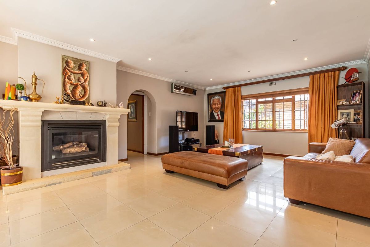 Spacious living room featuring a large stone fireplace, tiled flooring, recessed lighting, and an arched doorway leading to adjacent areas.