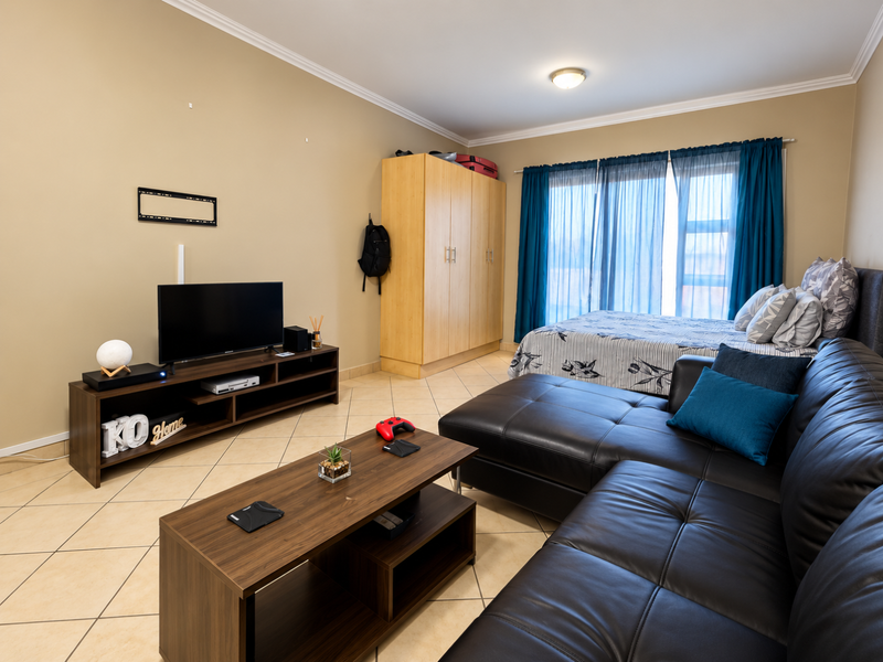 Open-plan living and sleeping area featuring tiled flooring, a built-in wardrobe, and access to a balcony through sliding doors.