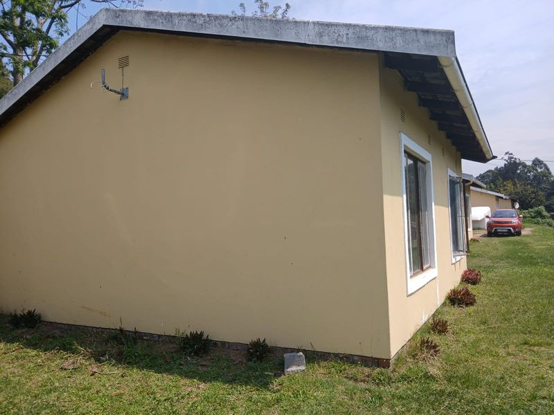 Side view of the property exterior showing the building facade, roofline, and window frames set against a grassy yard.