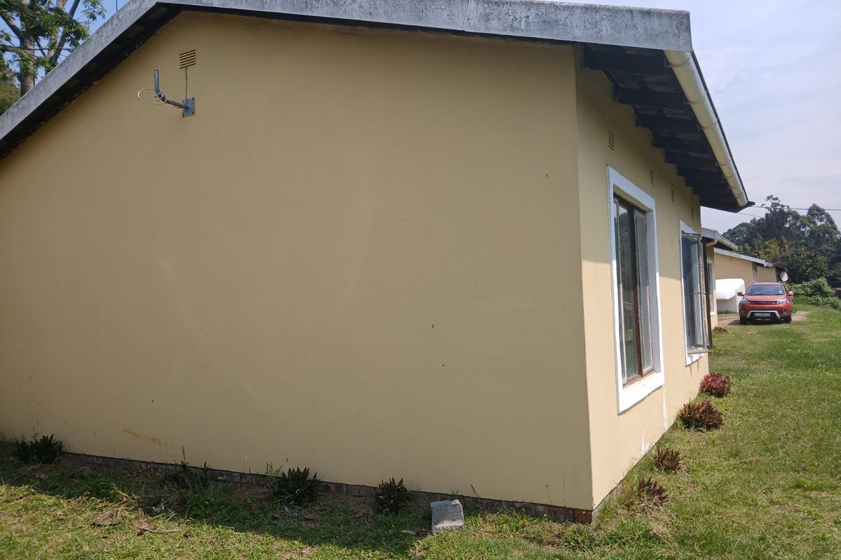 Side view of the property exterior showing the building facade, roofline, and window frames set against a grassy yard.