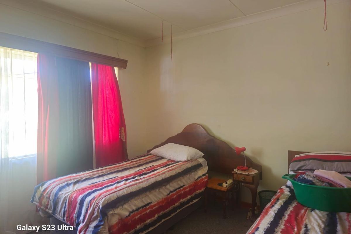 A bedroom featuring carpeted flooring, a window with curtain tracks, and standard ceiling finishes.