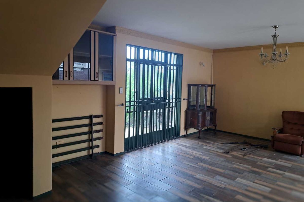 Spacious living area featuring wood-look tiled flooring, built-in cabinetry, and a secure metal gate leading to the exterior.