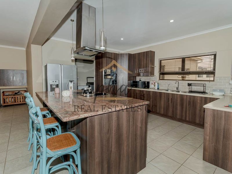 Modern kitchen featuring dark wood cabinetry, granite countertops, a central island with breakfast bar, and integrated stainless steel appliances.