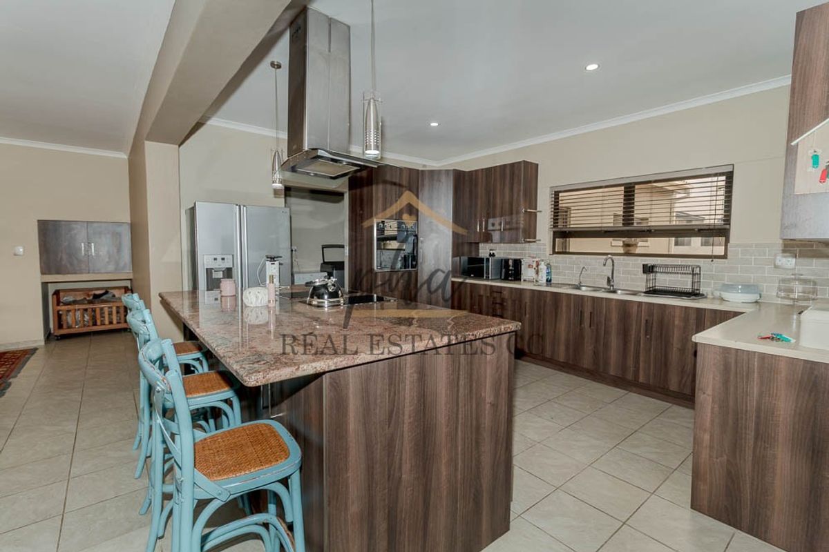 Modern kitchen featuring dark wood cabinetry, granite countertops, a central island with breakfast bar, and integrated stainless steel appliances.