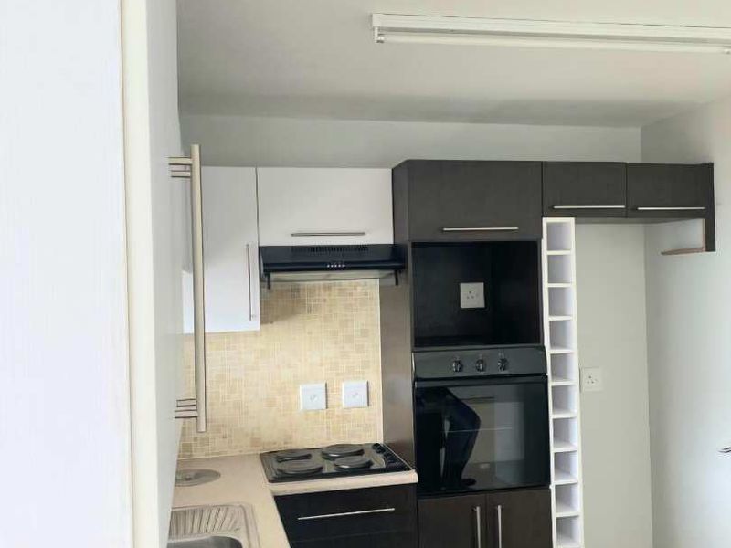 A functional kitchen featuring built-in oven, hob, extractor fan, double sink, and ample cabinetry with a dedicated wine rack.