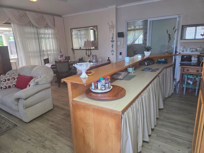 Open-plan living area featuring a breakfast bar, laminate flooring, and sliding glass door access to the exterior.