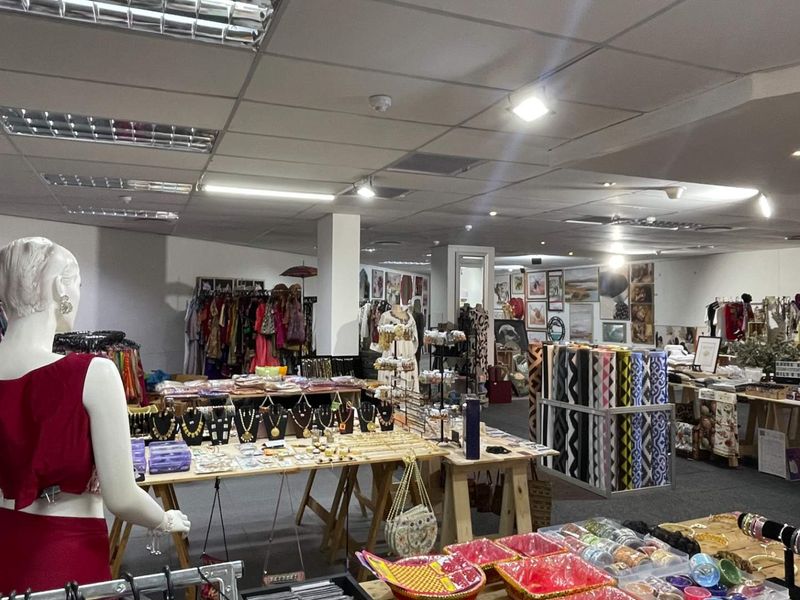 Open-plan retail space featuring a suspended ceiling with recessed lighting and carpeted flooring, currently utilized as a clothing and accessories boutique.