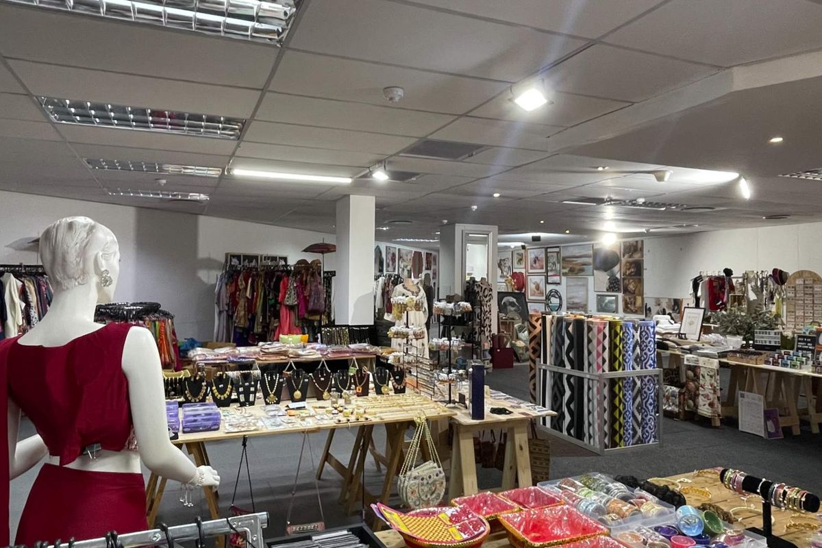 Open-plan retail space featuring a suspended ceiling with recessed lighting and carpeted flooring, currently utilized as a clothing and accessories boutique.