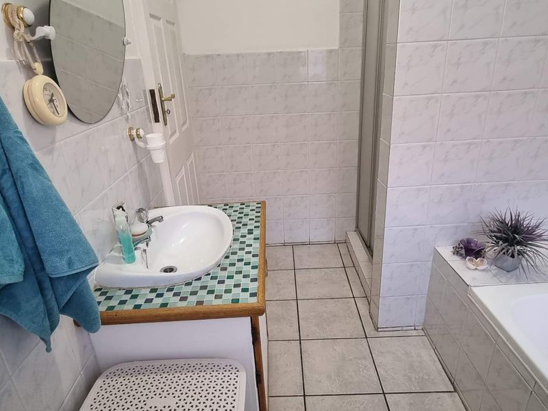 A functional bathroom featuring a built-in vanity with a drop-in sink, a separate shower enclosure, and a tiled bathtub surround.