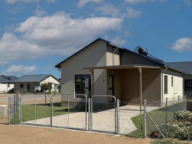 Front exterior view of a modern townhouse featuring a paved driveway, fenced yard, and solar geyser installation.