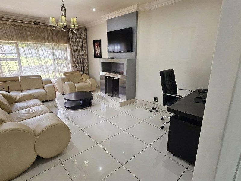 Spacious living room featuring large format floor tiles, a modern built-in fireplace with integrated television mount, and decorative cove cornicing.
