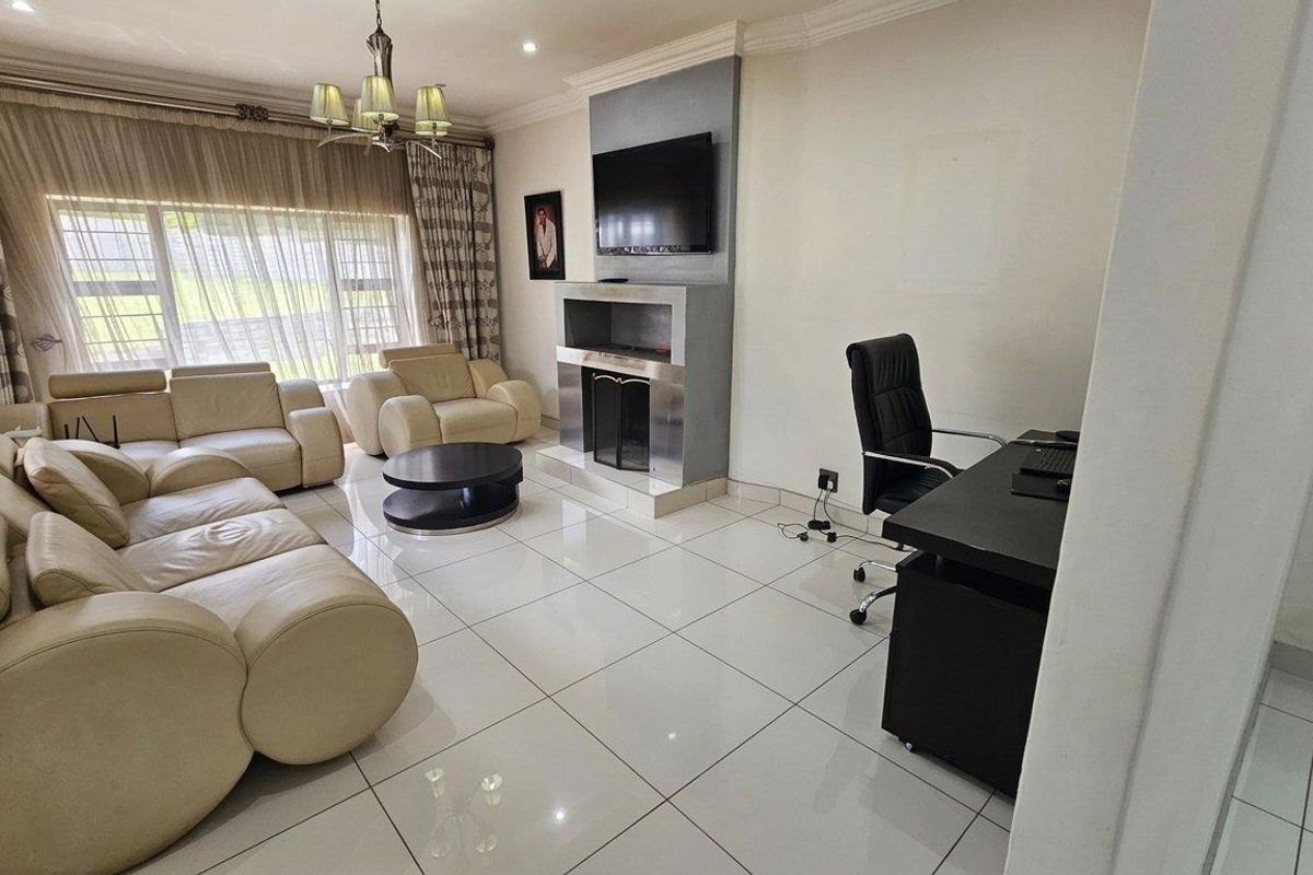 Spacious living room featuring large format floor tiles, a modern built-in fireplace with integrated television mount, and decorative cove cornicing.