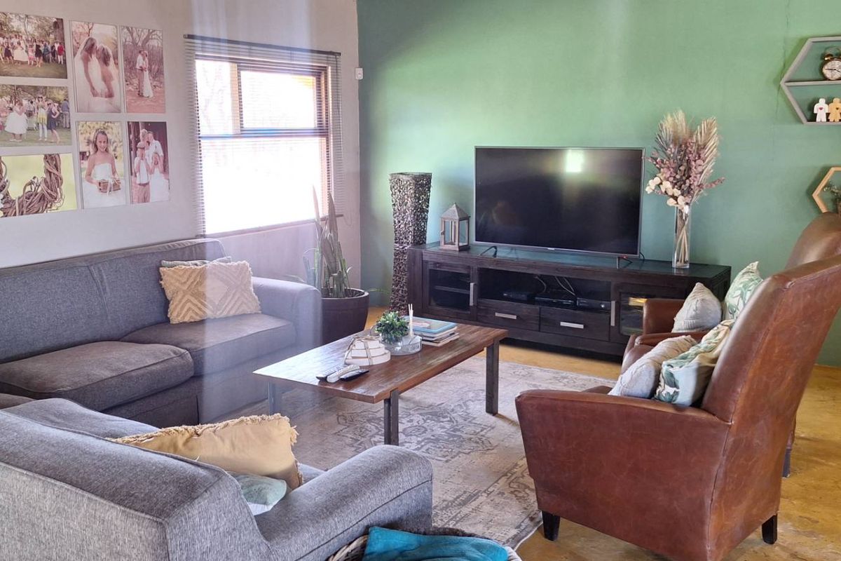 A comfortable living room featuring a large accent wall, tiled flooring, and natural light from the side window.