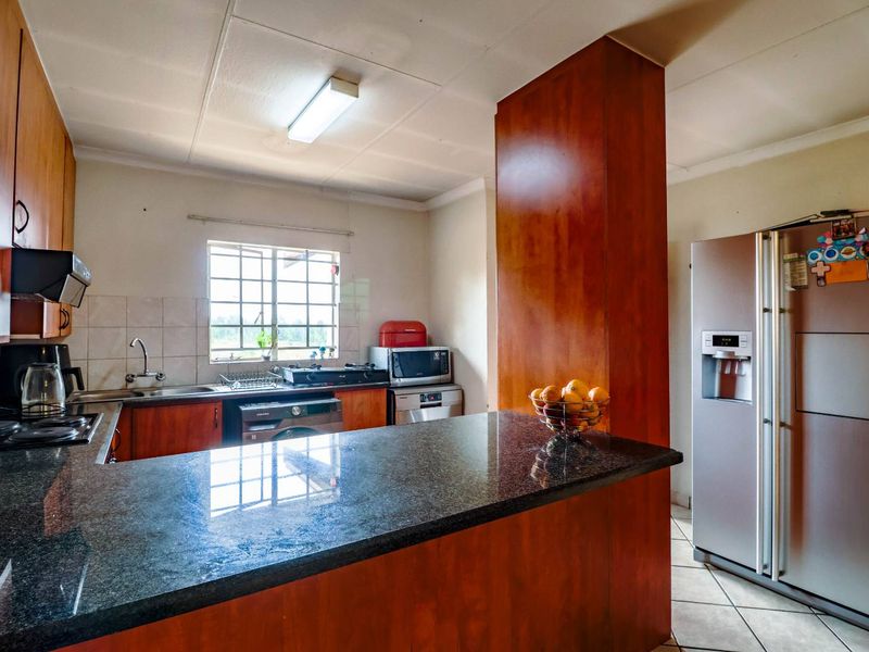 A functional kitchen featuring granite countertops, wooden cabinetry, and a breakfast bar, offering a practical layout with integrated appliances and ample storage space.