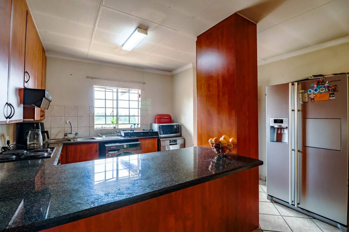 A functional kitchen featuring granite countertops, wooden cabinetry, and a breakfast bar, offering a practical layout with integrated appliances and ample storage space.