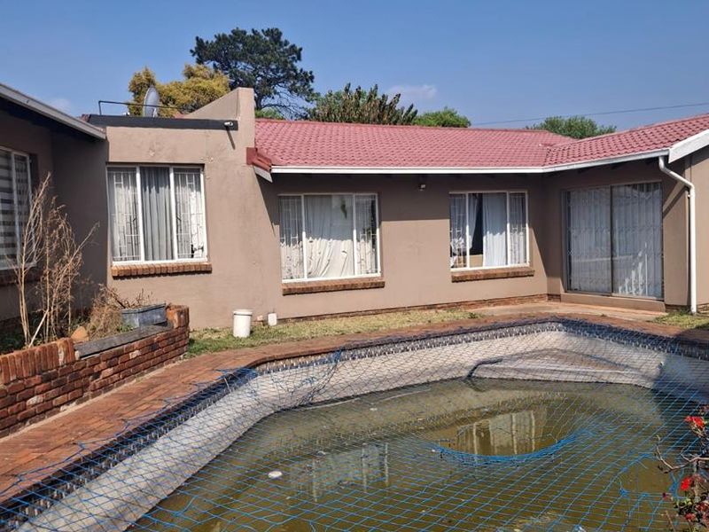 Rear exterior view featuring a swimming pool with a safety net, brick paved surround, and access to the main house via sliding glass doors.