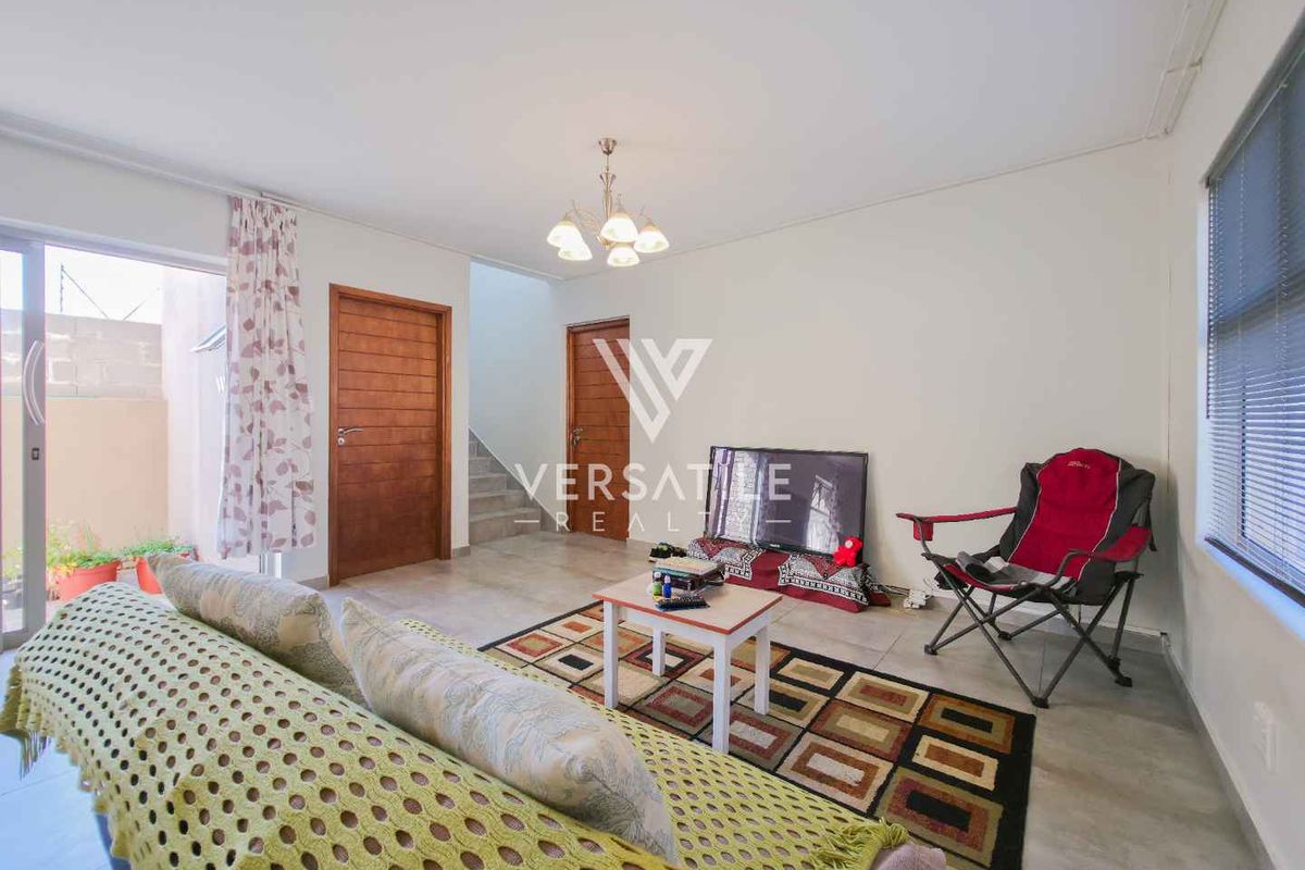 A bright living room featuring tiled flooring, sliding glass doors leading to an outdoor area, and a staircase leading to the upper level.