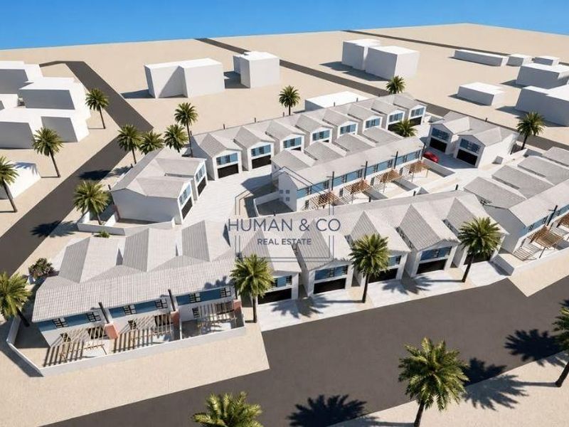 An aerial 3D render showing the layout of a townhouse development complex with multiple units, garages, and landscaped outdoor areas.