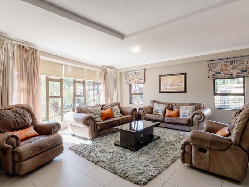 A spacious and bright living room featuring large windows, neutral tiled flooring, and a modern recessed ceiling design.