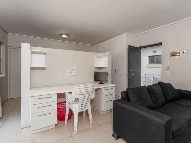 A functional living area featuring a built-in desk workspace, ample built-in cabinetry, and neutral tiled flooring, providing a practical layout for daily living.
