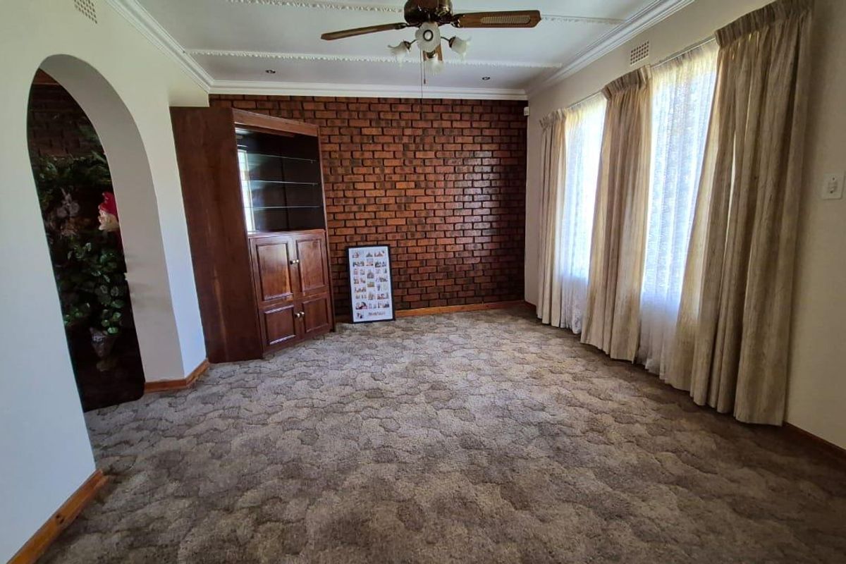 A living room featuring a prominent exposed brick feature wall, decorative ceiling cornice, and a central ceiling fan.
