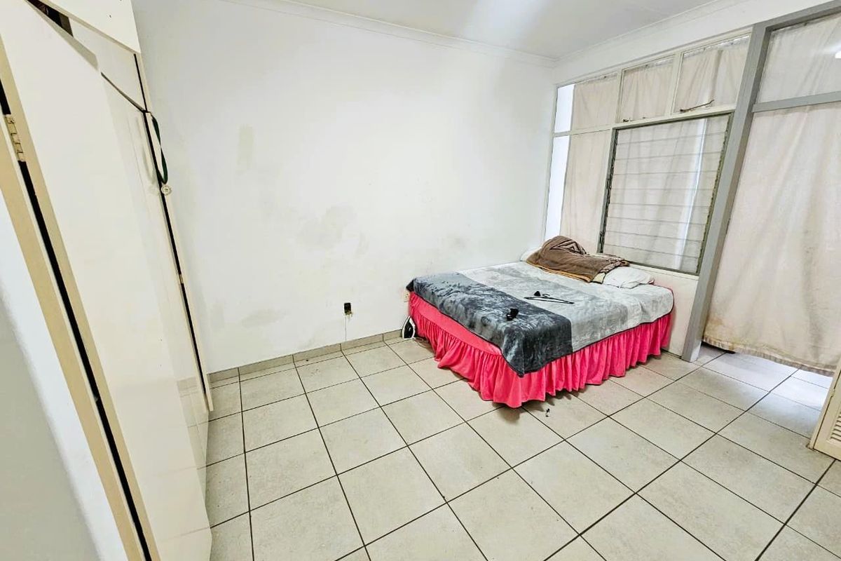 A bedroom featuring tiled flooring, built-in wardrobe, and large windows with curtains, requiring cosmetic updates to improve its overall condition.