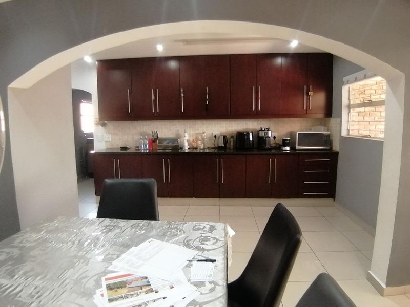A functional kitchen featuring dark wood cabinetry, granite countertops, and tiled flooring, framed by a decorative architectural archway.
