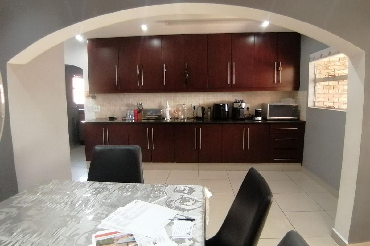 A functional kitchen featuring dark wood cabinetry, granite countertops, and tiled flooring, framed by a decorative architectural archway.