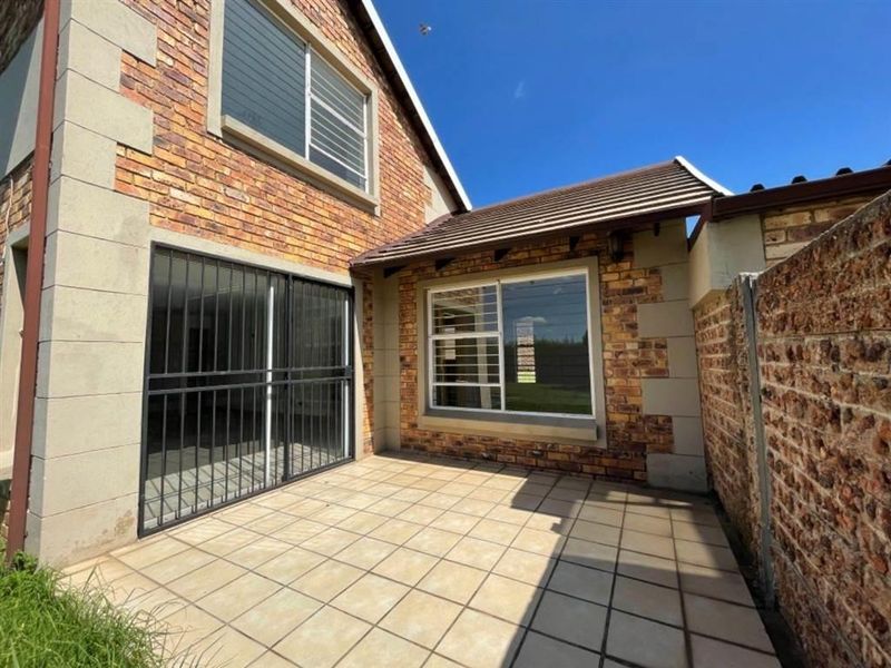 A private rear patio area featuring tiled flooring, facebrick exterior walls, and secure access points, providing a functional outdoor space.
