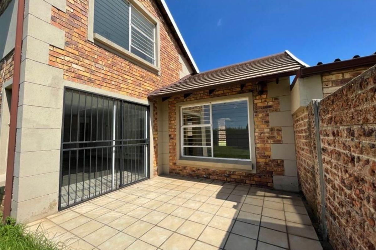 A private rear patio area featuring tiled flooring, facebrick exterior walls, and secure access points, providing a functional outdoor space.