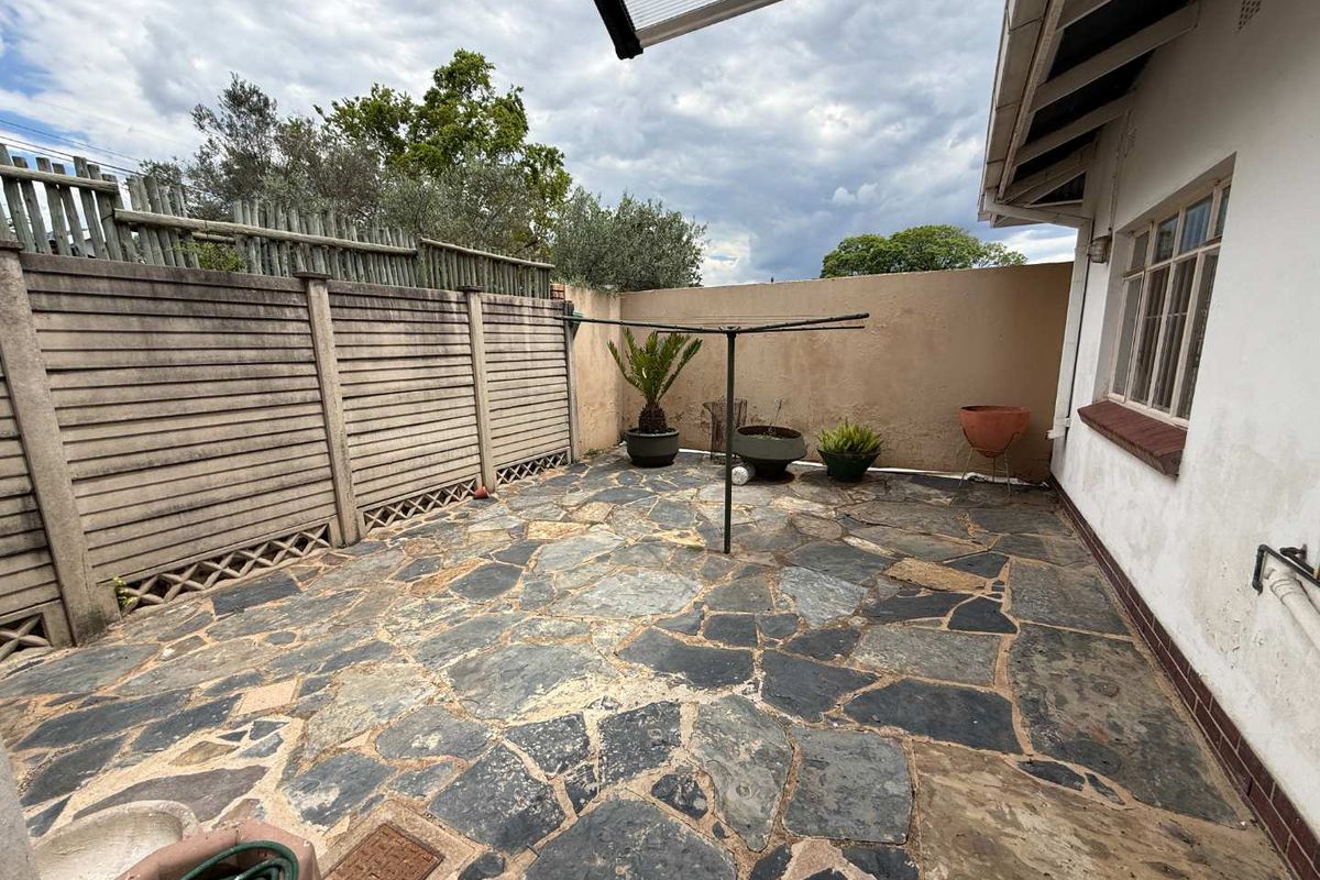 A private rear courtyard featuring natural stone paving, enclosed by boundary walls and fencing, providing a functional outdoor space.
