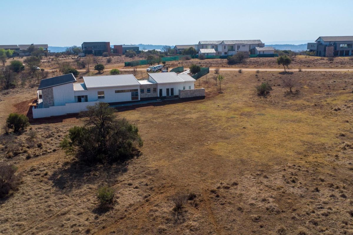 Aerial view of a modern residential property featuring a metal roof and stone cladding, situated within a spacious, undeveloped landscape.