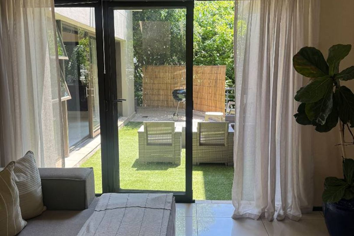 A bright living room featuring large sliding glass doors that provide seamless access to an outdoor patio and garden area.