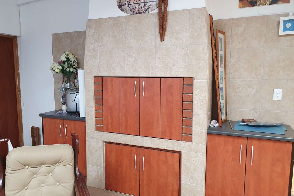 Indoor built-in braai area featuring tiled surround, wooden cabinetry, and integrated storage compartments.