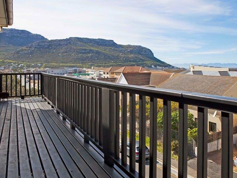An elevated balcony featuring timber decking and a matching balustrade, offering expansive views of the surrounding neighborhood and mountain landscape.