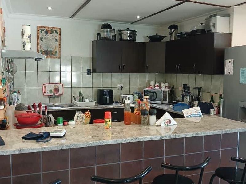 A functional kitchen featuring a tiled breakfast bar, granite countertops, dark cabinetry, and recessed ceiling lighting.
