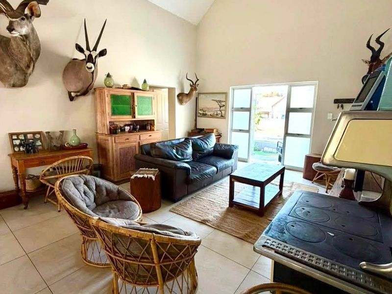 Spacious living area featuring high vaulted ceilings, large glass sliding doors for natural light, tiled flooring, and a traditional cast iron stove.