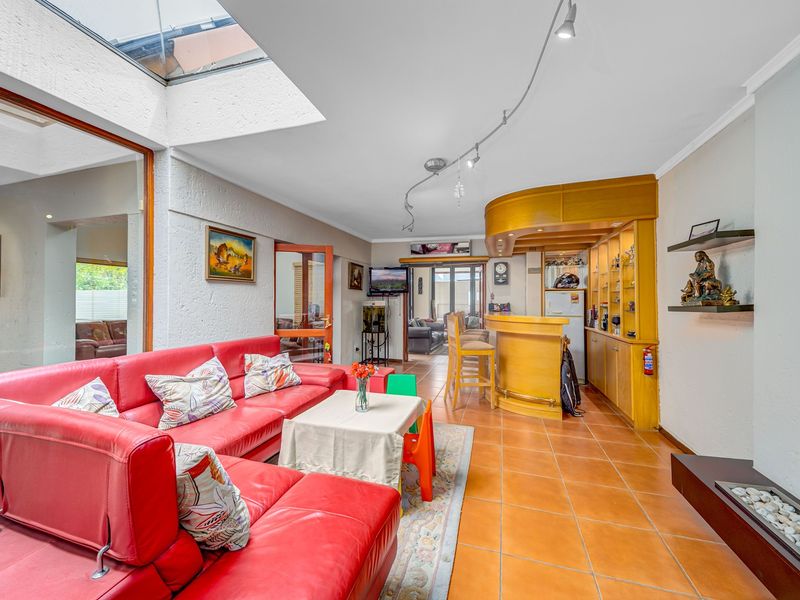 Spacious living area featuring a built-in bar, tiled flooring, a fireplace, and a large skylight providing ample natural light.