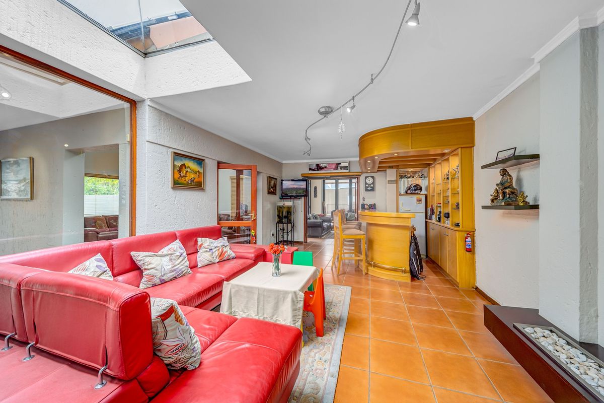 Spacious living area featuring a built-in bar, tiled flooring, a fireplace, and a large skylight providing ample natural light.