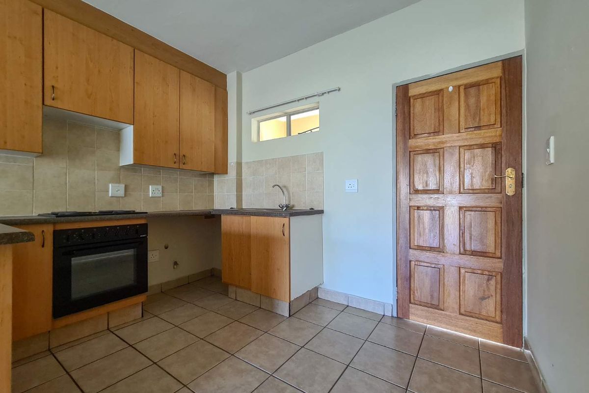 A functional kitchen featuring wooden cabinetry, built-in oven, tiled backsplash, and tiled flooring, offering a clean and practical space ready for updates.