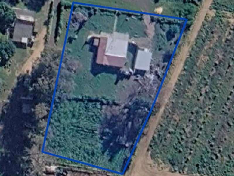 Aerial view of the property showing the main dwelling, outbuilding, and surrounding land within the fenced boundary.