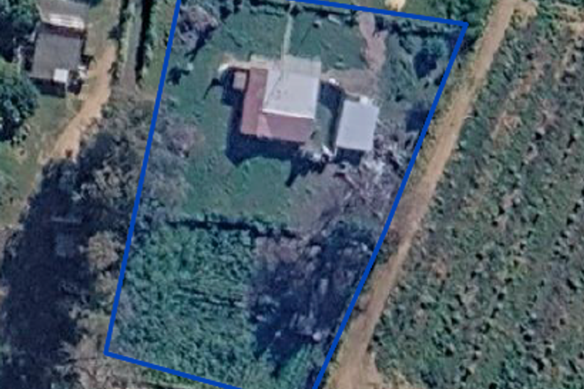 Aerial view of the property showing the main dwelling, outbuilding, and surrounding land within the fenced boundary.